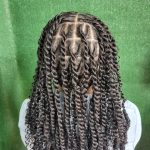 A woman with long, curly hair is shown with a twist, looking elegant and stylish.